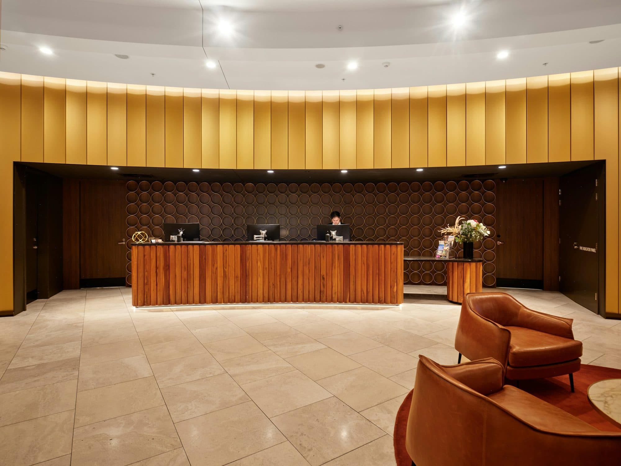 A warmly lit hotel reception in wood, with lounge chairs.