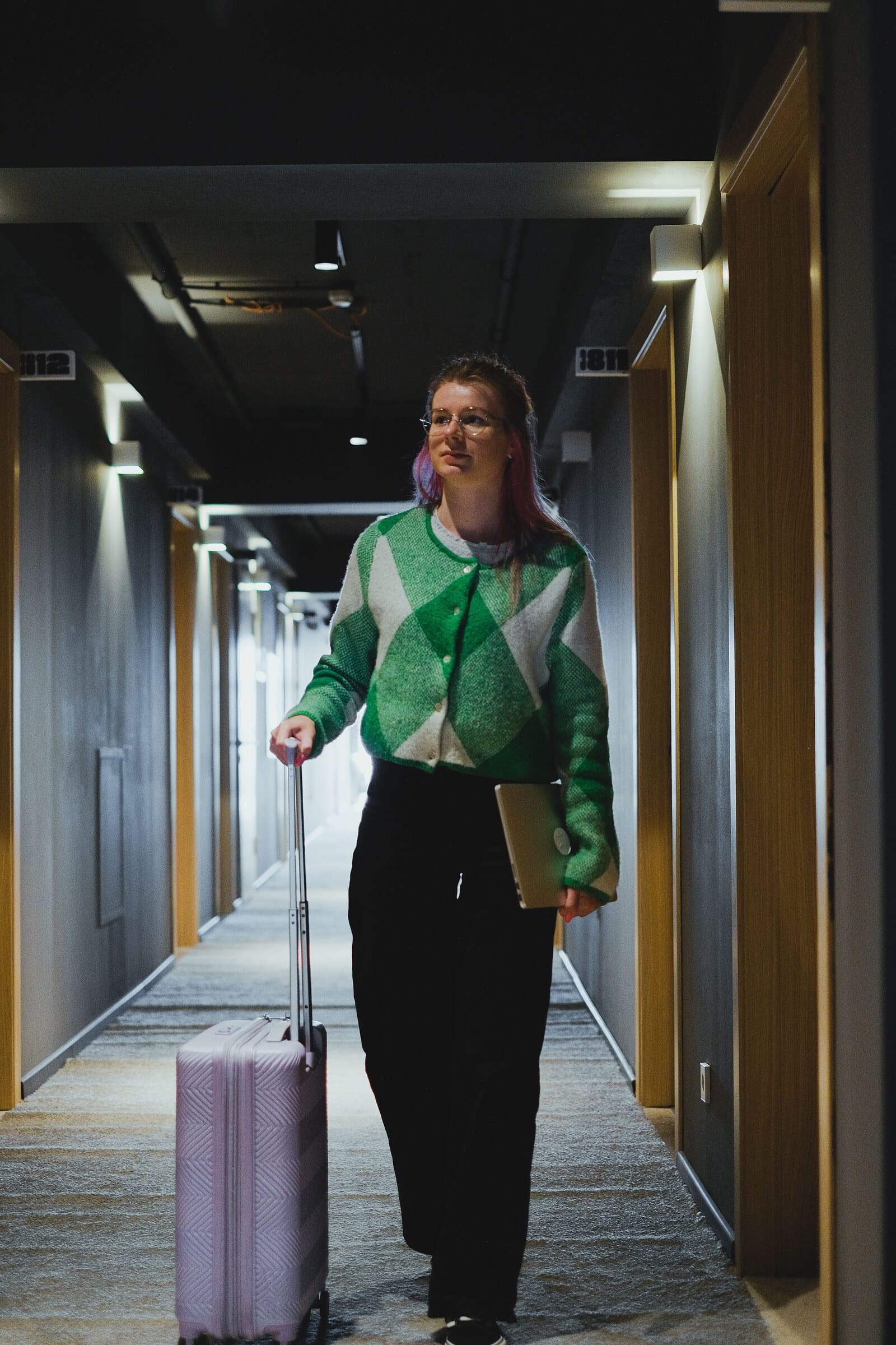 Presence Hospitality: a guest with her suitcase walking to her room along a modern hotel corridor.