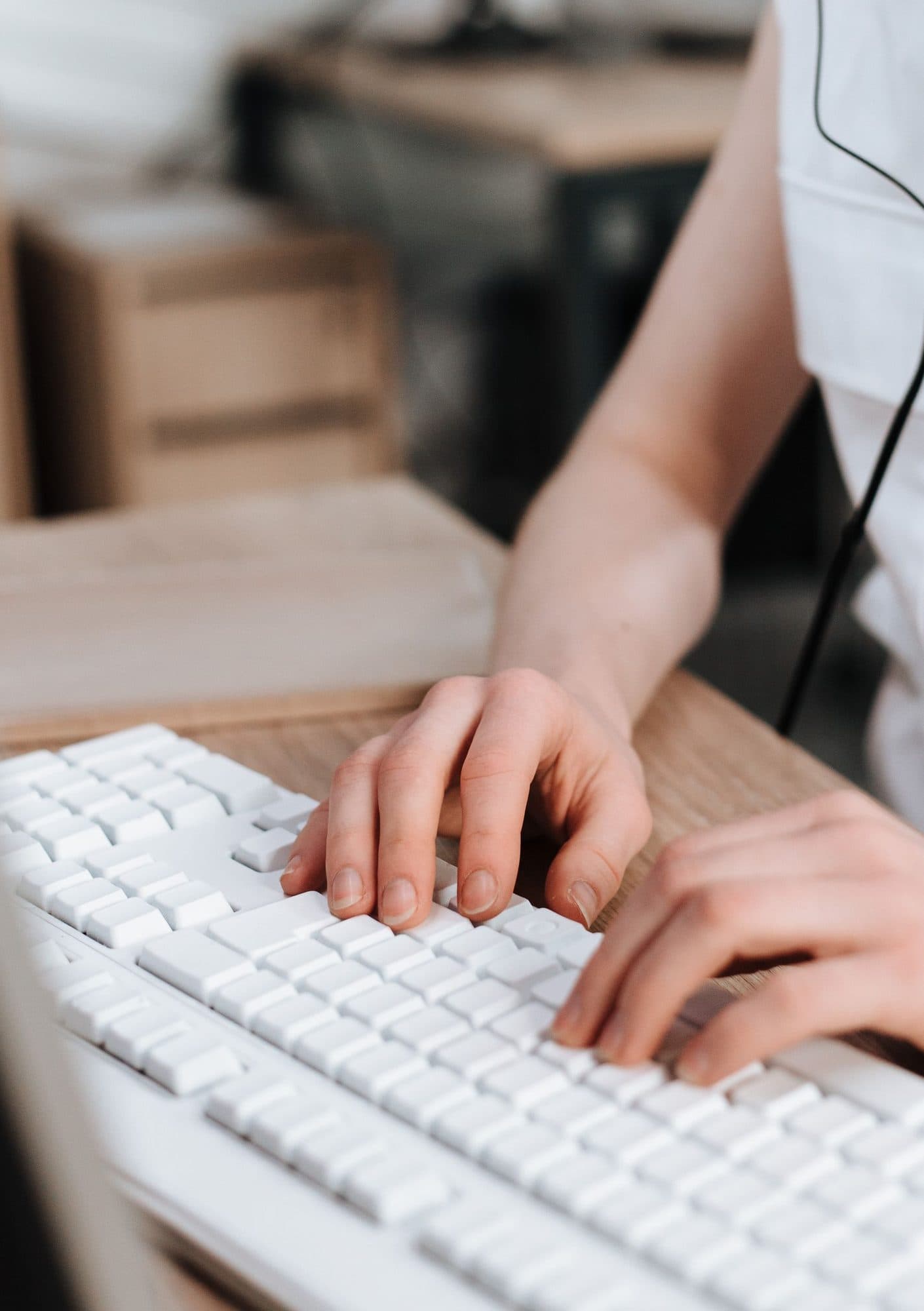 Hands on a keyboard and a headset at a reception workstation.
