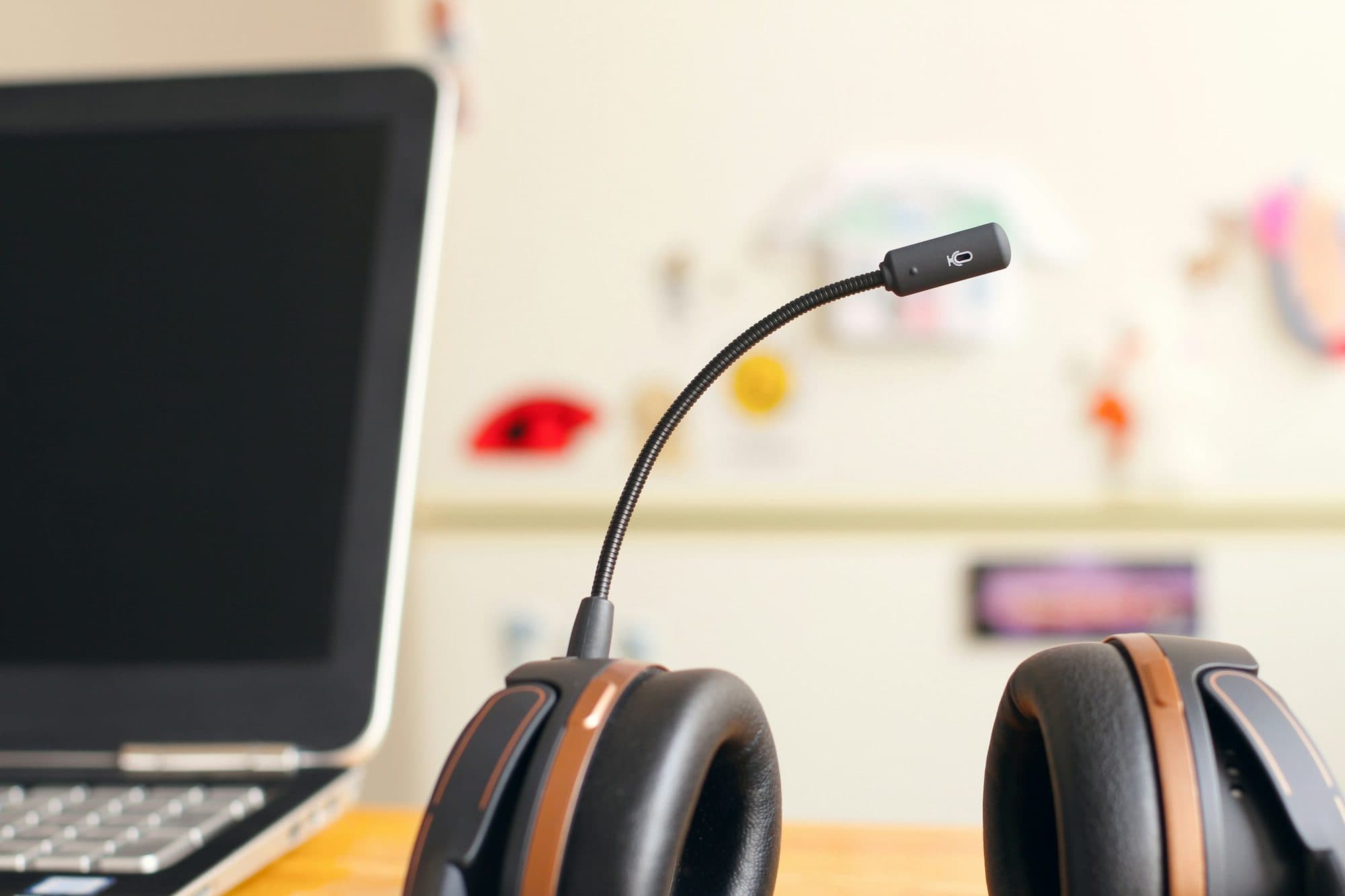 A headset resting beside a laptop on a desk.