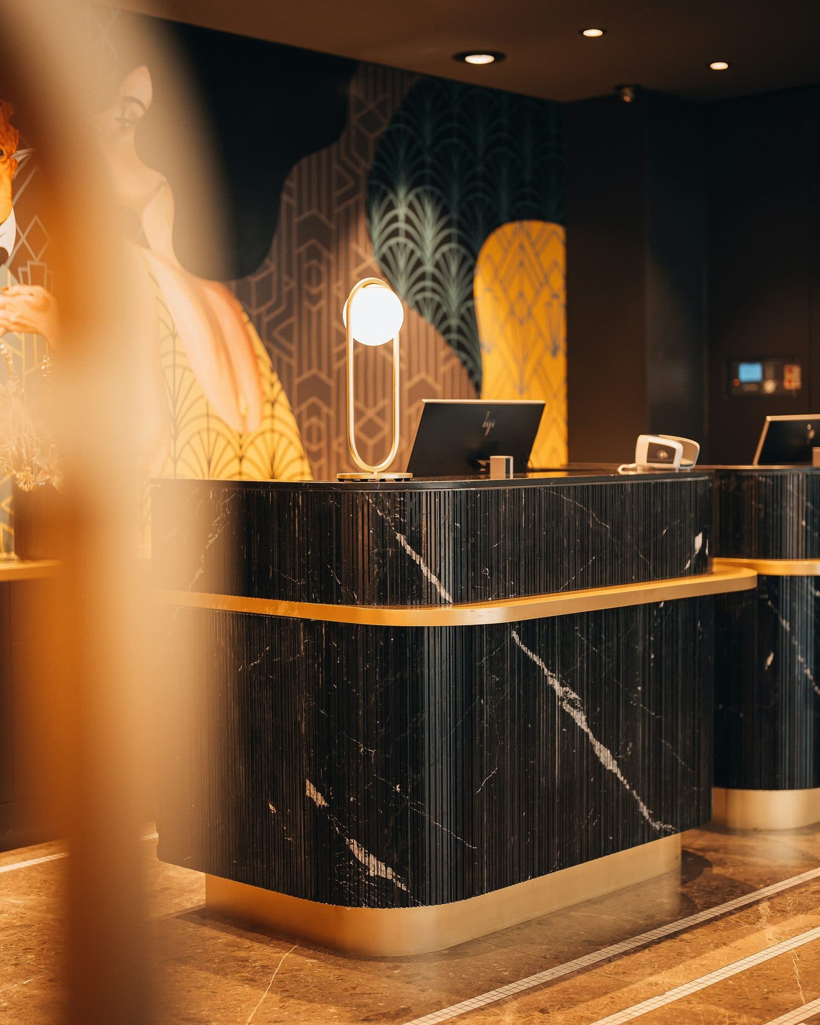 An empty hotel reception desk in marble and brass, late in the evening.