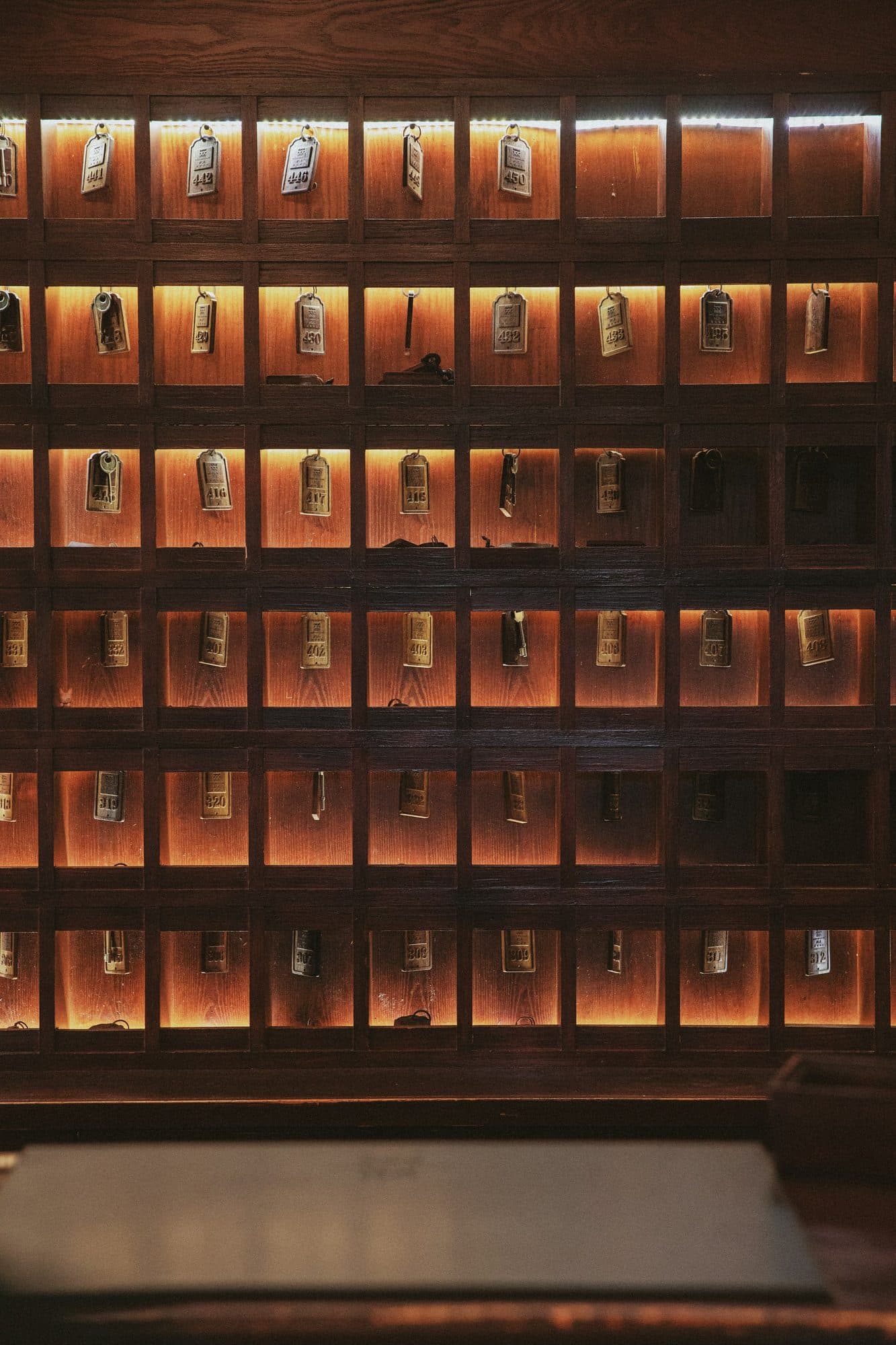A wall of hotel room keys in warmly lit wooden cubbies.